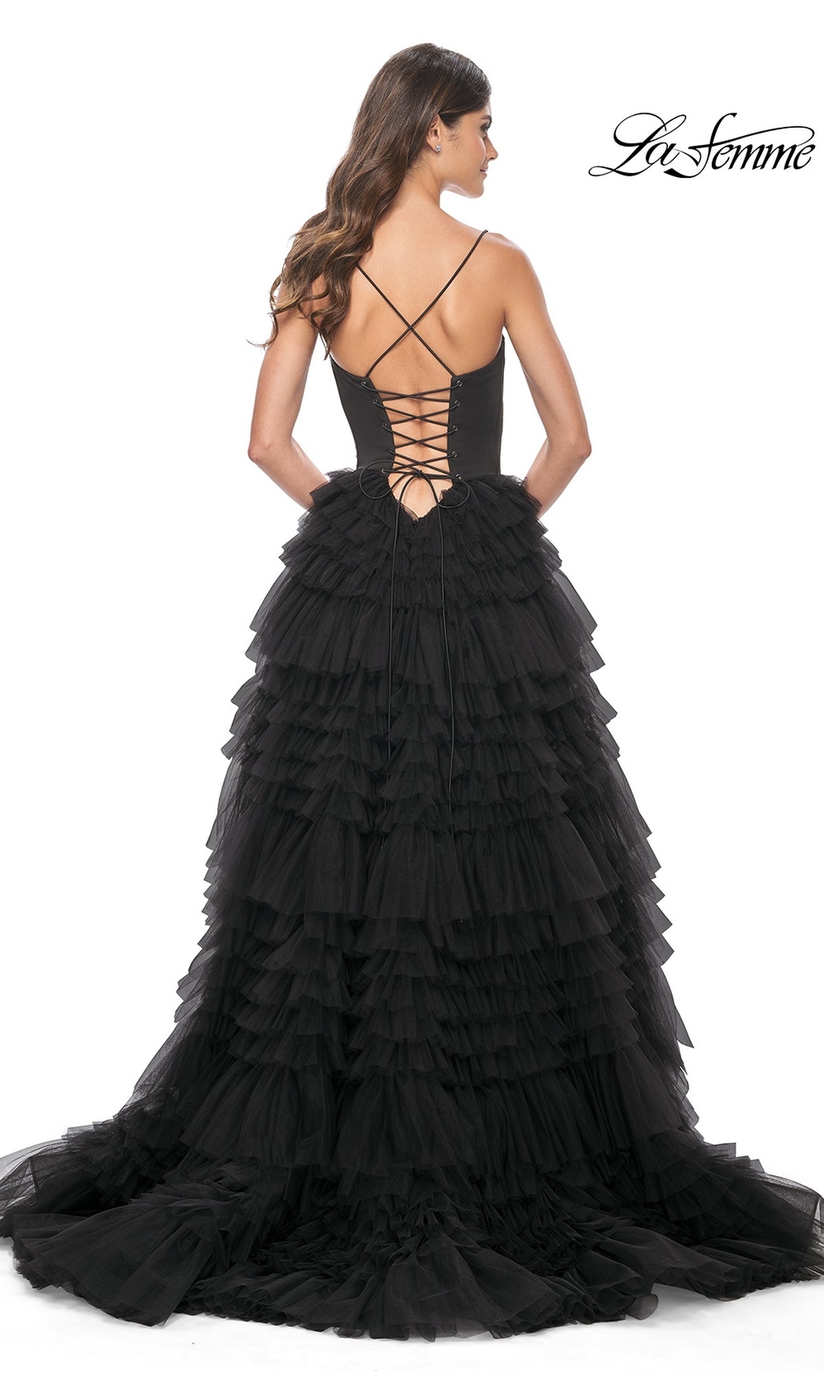 A woman stands against a white background wearing the La Femme 32071 Lace-Up Ruffle Long Prom Ball Gown, a black tiered tulle dress featuring an open lace-up back and sweetheart corset bodice.